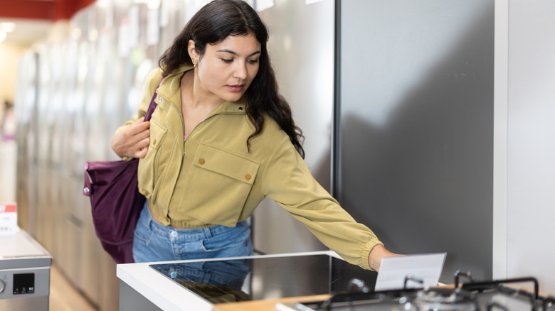 person looking at the price tag on an induction-top range in an appliance store