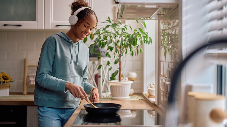 person wearing headphones while cooking on an induction stovetop set into a countertop