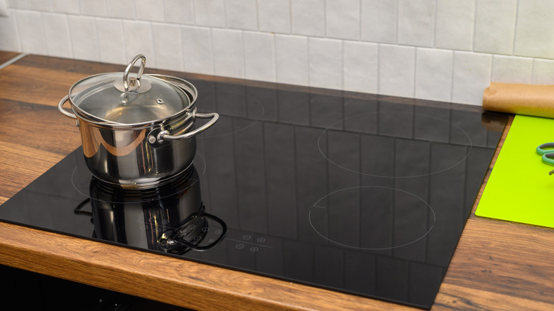 pot sitting on an induction stovetop set into a wooden kitchen countertop