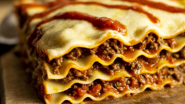 A closeup of a slice of lasagna on a wooden plate