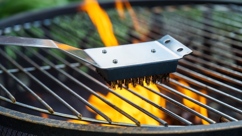 Person using grill brush to clean grill grates