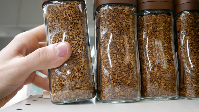 hand removing jar of instant coffee from store shelf