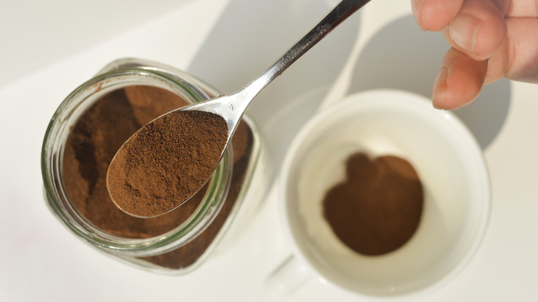 instant coffee in a spoon, a mug, and a jar