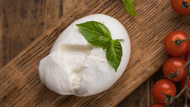 A ball of broken-open burrata on a wooden surface