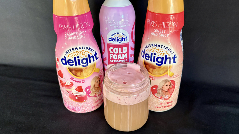 three International Delight creamers behind coffee with pink foam on top