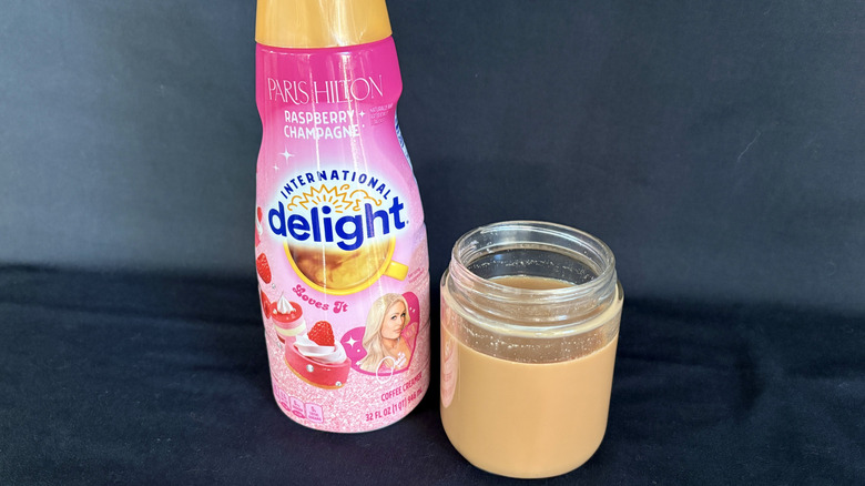 bottle of creamer next to clear glass of coffee