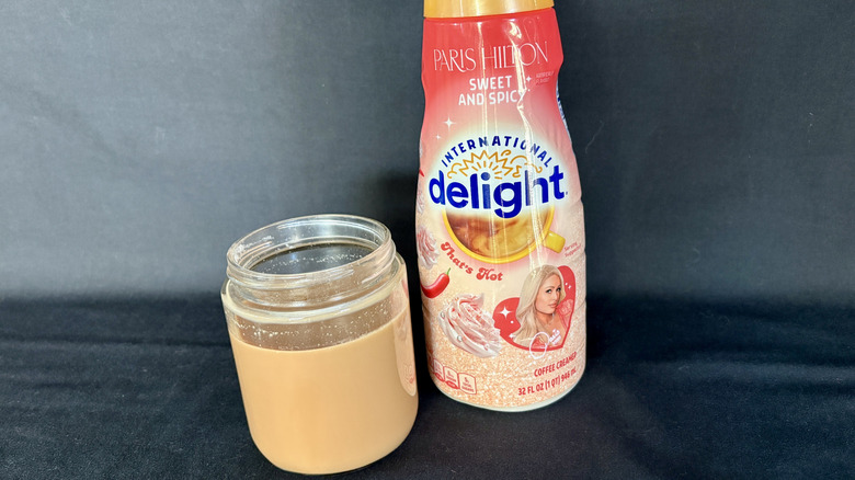 bottle of creamer next to clear glass of coffee