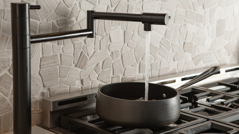 Water flows from a pot filler into a pan on a stove