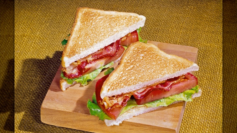 Blt sandwich cut in half on wood block