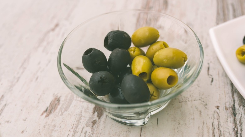 Black and green olives in glass bowl