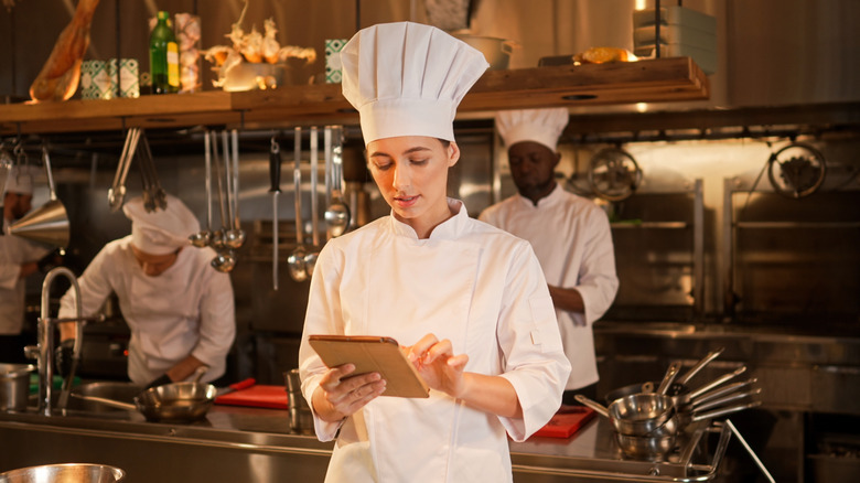 A chef checks a list in a busy kitchen