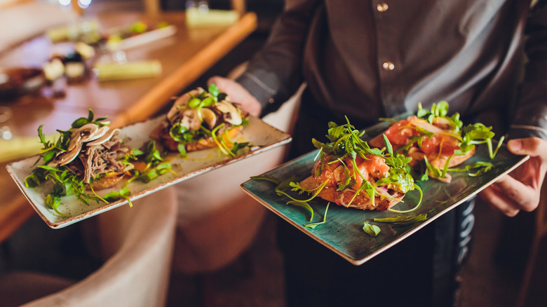 A server delivering dishes to a table at a restaurant