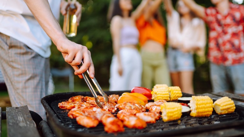 Man grilling while friends have a toast in the background