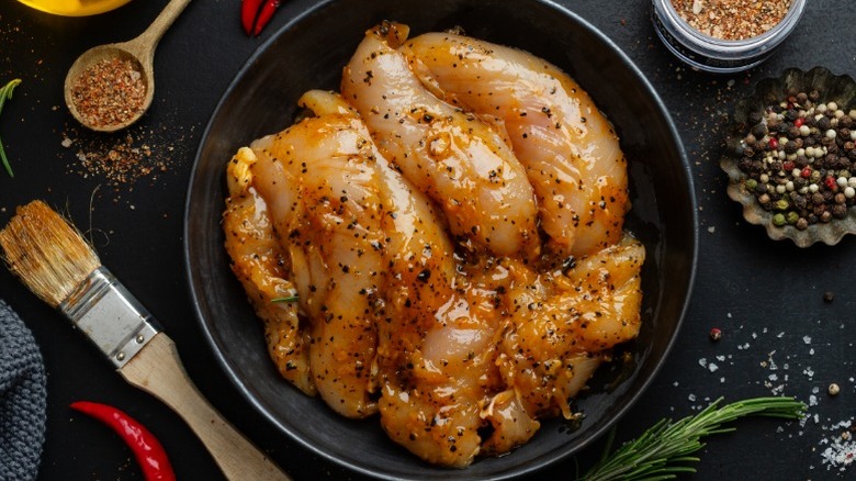 Chicken breasts with seasoning in a bowl of marinade