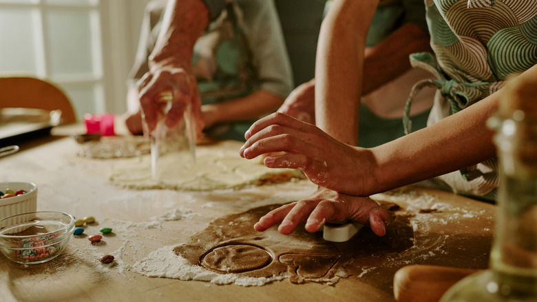 Adult and child hands cutting out cookies