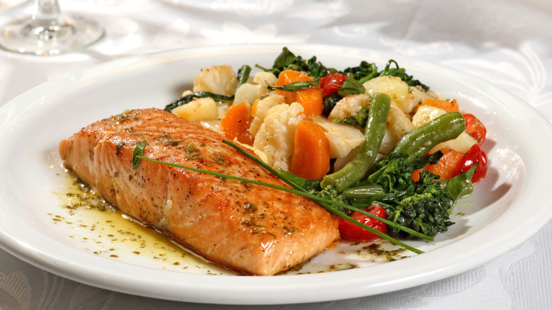 Plate of cooked salmon surrounded by veggies at a restaurant