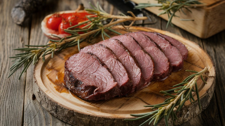 Smoked and sliced venison tenderloin on wooden cutting board