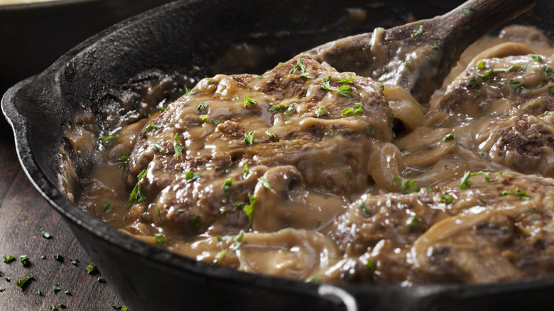 Salisbury steak being stirred in a cast iron pan