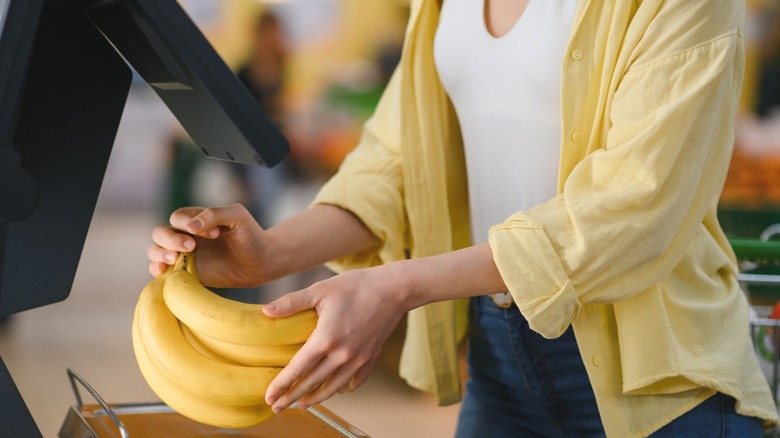A woman using self-checkout for her groceries.