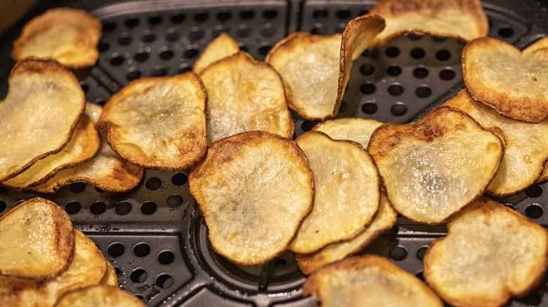 Golden brown potato chips in an air fryer basket