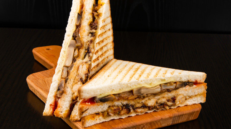 Two halves of a toasted club sandwich with melted cheese and meat