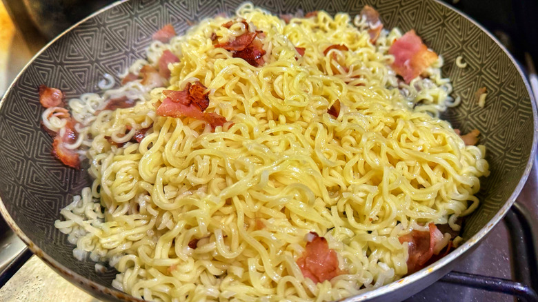 a skillet full of ramen noodle carbonara
