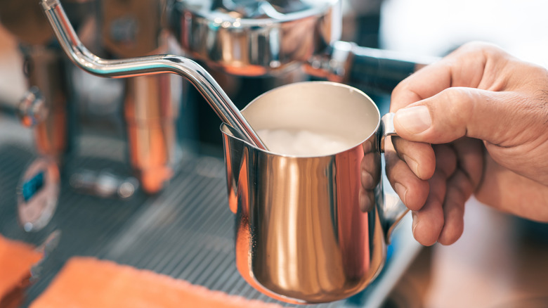 Barista using high pressure wand to steam milk