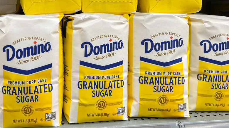 Bags of Domino sugar on a store shelf.