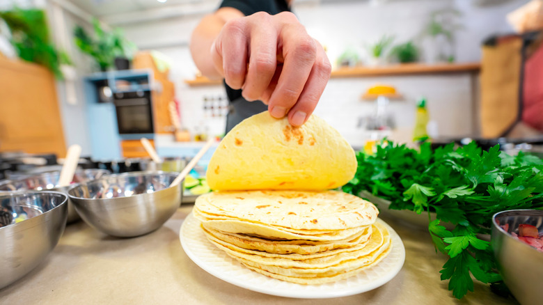 A person preparing homemade tortillas on a kitchen counter