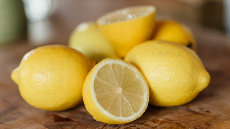 Fresh lemons cut in half on a wooden board