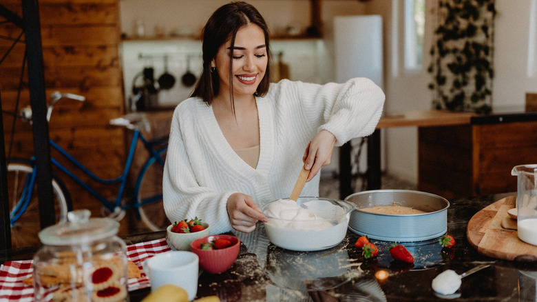 Young woman preparing cheesecake at home