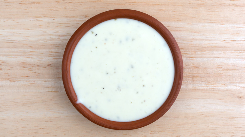 Top down image of a bowl of ranch dressing on a wooden table.