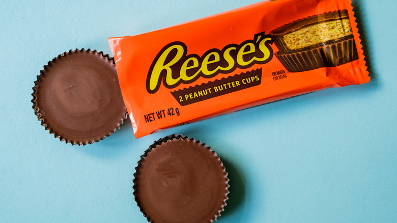 A Reese's Peanut Butter Cup package with two peanut butter cups beside it
