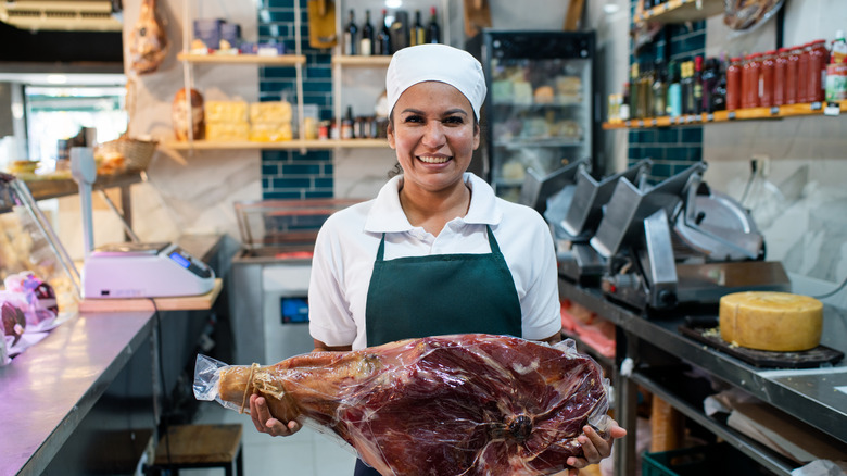 A smiling butcher holding a ham