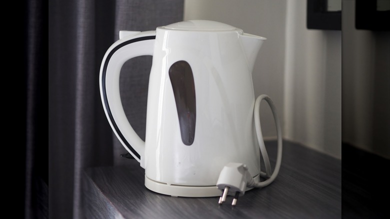 An unplugged electric kettle with white plastic exterior sitting on a surface.
