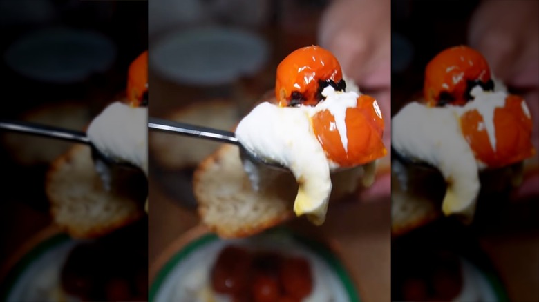Close-up of cherry tomatoes and buffalo mozzarella being spread on toasty bread