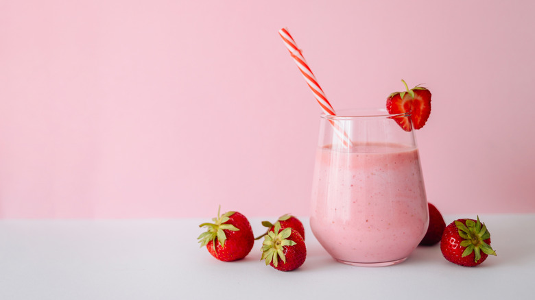 strawberry milk in glass with fresh strawberries next to it