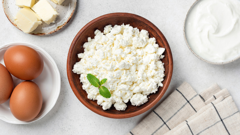 Overhead shot of bowl of cottage cheese near eggs, butter, and cream