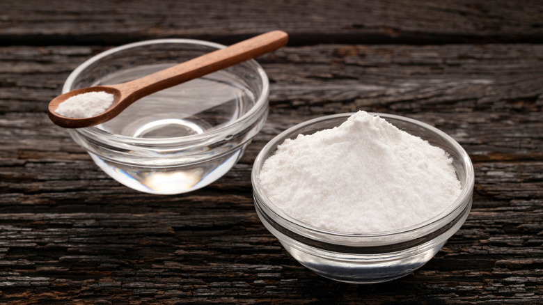 A bowl of baking soda sitting next to a bowl of water.