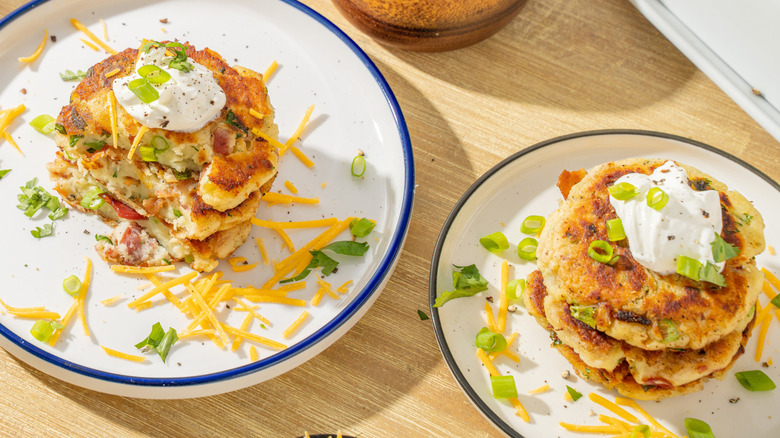 Top view of savory pancakes with sour cream, cheese and green onions