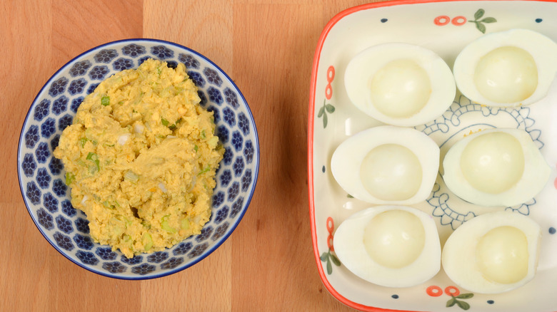 A dish of boiled egg whites with a bowl of mashed egg yolks