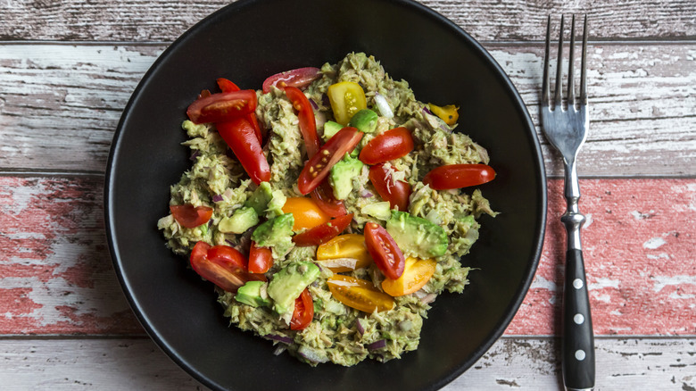 Tuna salad served in a black plate with a fork on the side.