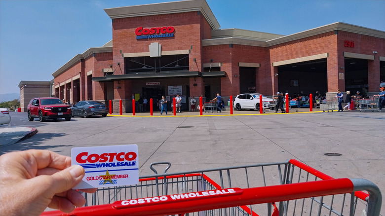Person with Costco card and cart outside the store