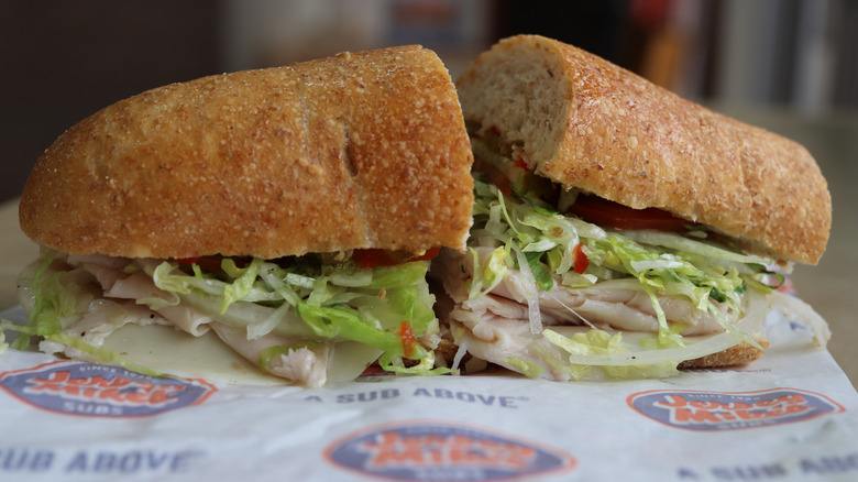 Sub sandwich with turkey and shredded lettuce cut in half on Jersey Mike's paper wrap
