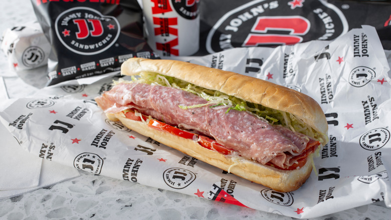 Jimmy John's Italian sandwich on countertop with chips, drink, packaging.