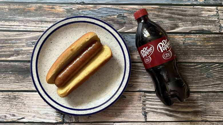 A Johnsonville Dr Pepper Inspired Sausage on a bun and a bottle of Dr Pepper