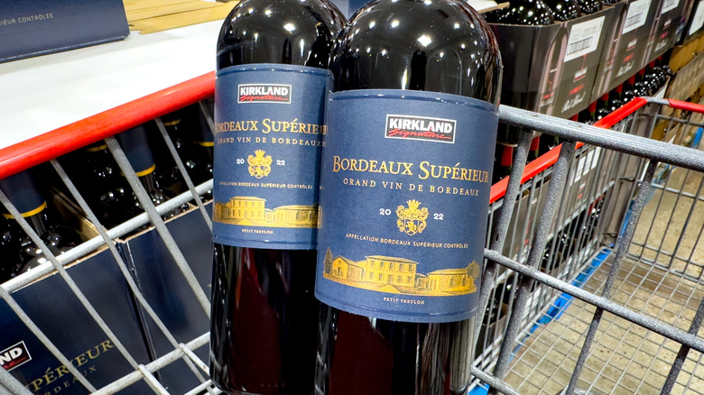 Two bottles of Kirkland Signature Bordeaux Superieur in a shopping cart.