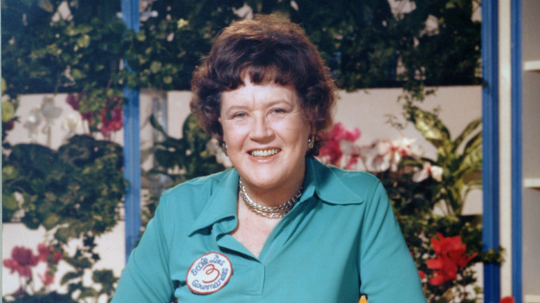 A portrait of the American chef Julia Child shows her standing with a cut of meat in her kitchen, late 20th century.