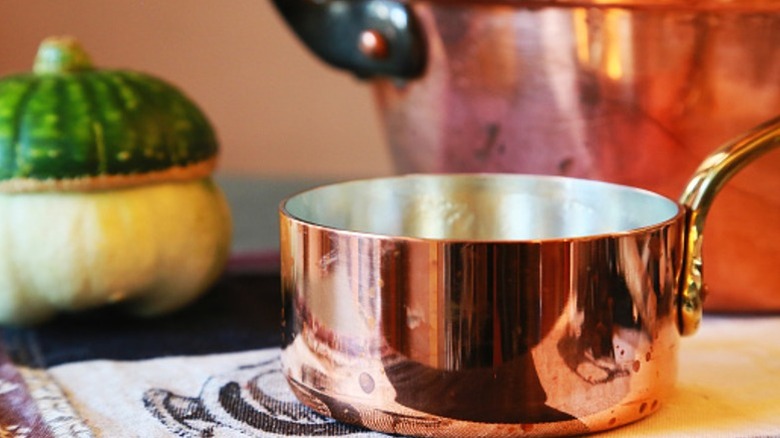 A copper pot on a dish towel near a cop