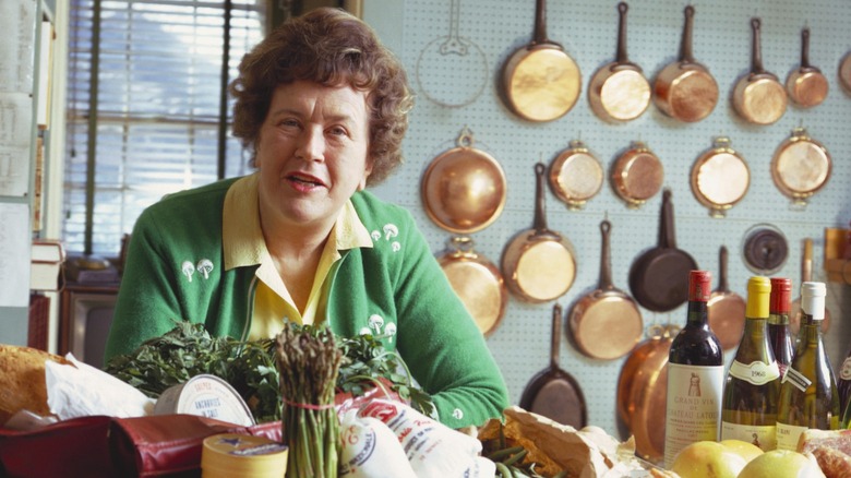 Julia Child, pictured in front of her numerous copper pots and pans mounted on the wall